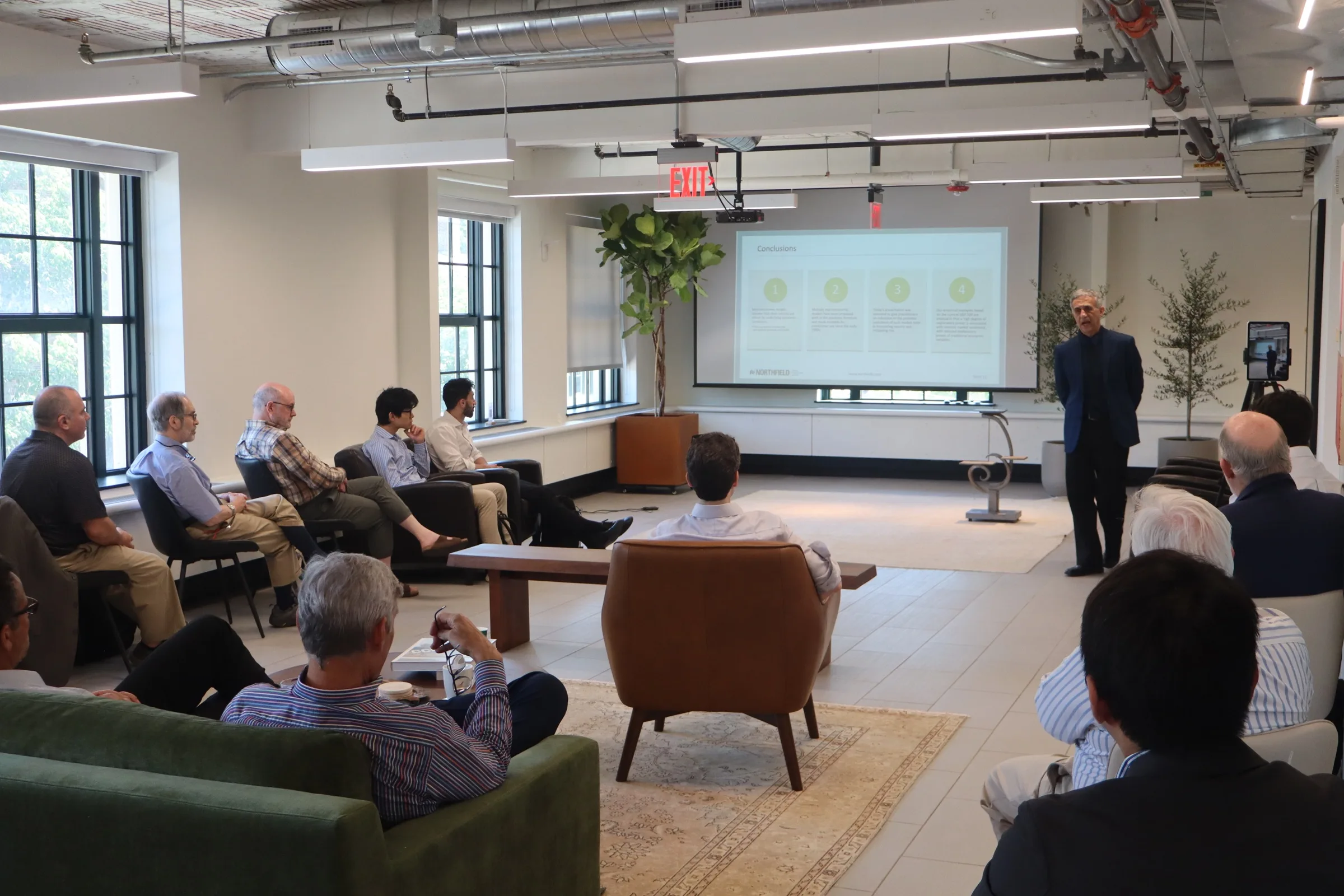Dan diBartolomeo presenting to a seated audience at Northfield Labs, a slide reading Conclusions behind him.